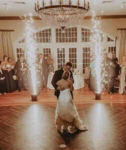 A bride and groom dance in front of sparklers at their wedding DJ service.
